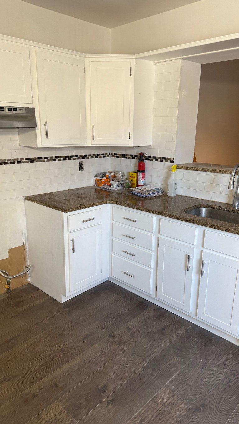 Modern kitchen with white cabinetry, gray granite countertops, subway tile backsplash with dark border, and dark wood flooring