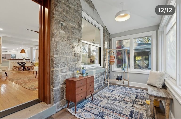 Modern entryway with stone accent wall, wooden vanity, patterned runner rug, and glass shower enclosure leading to open living space