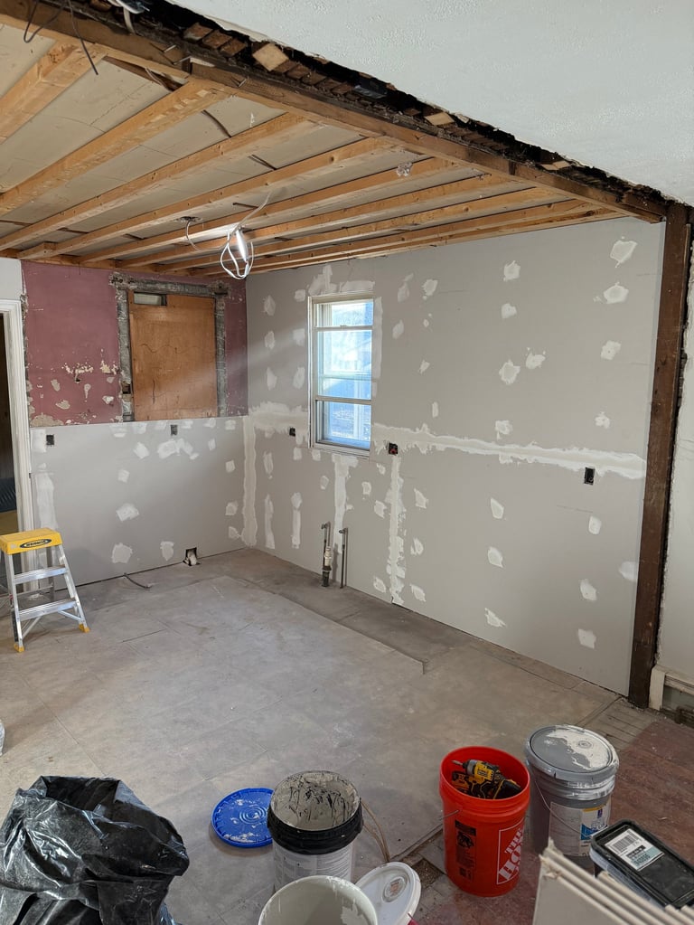 Interior room under renovation with exposed wooden beams and drywall patches