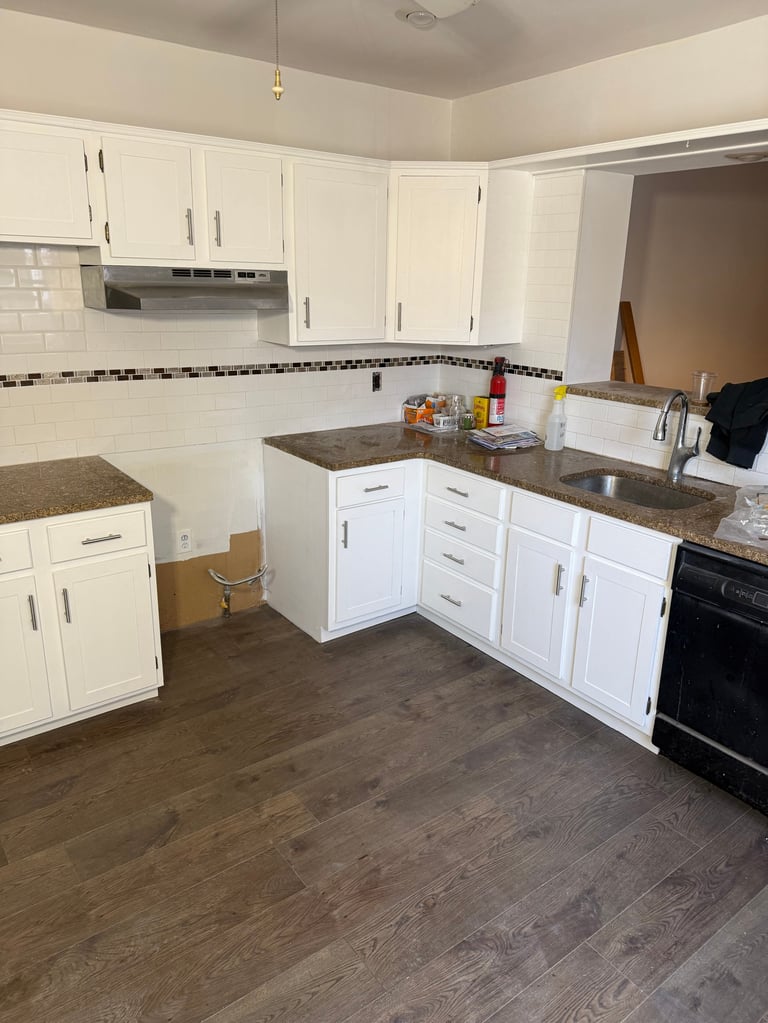 Modern kitchen with white cabinetry, gray countertops, subway tile backsplash, and dark wood-look flooring