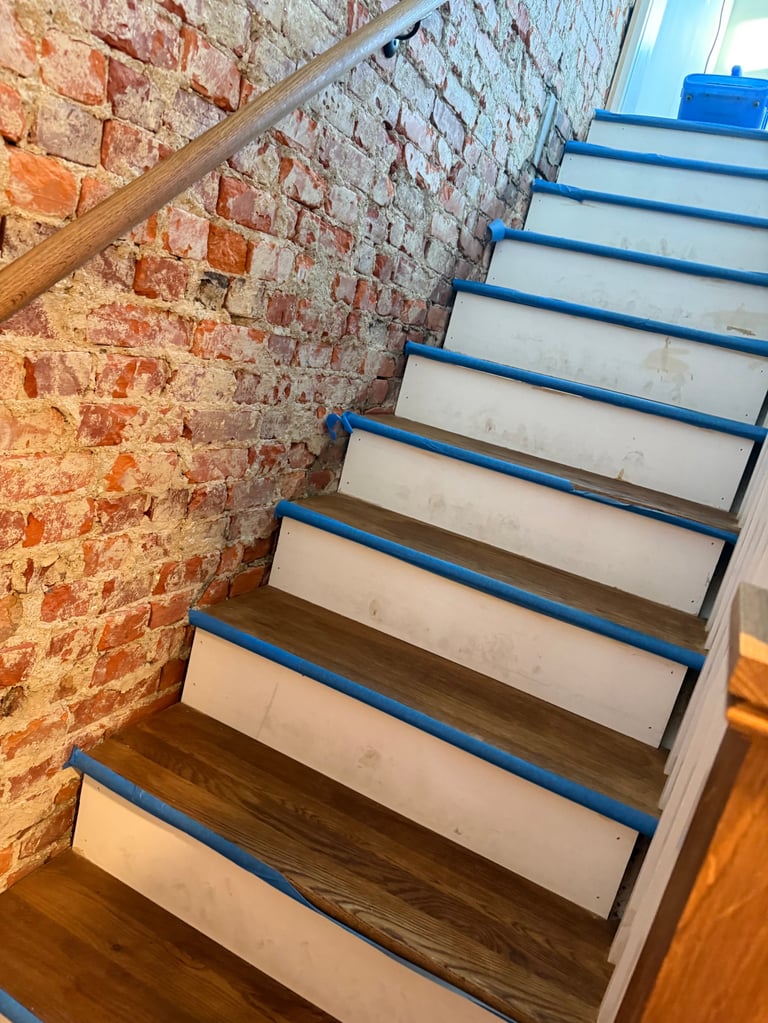 Wooden staircase with blue metal railings against exposed red brick wall