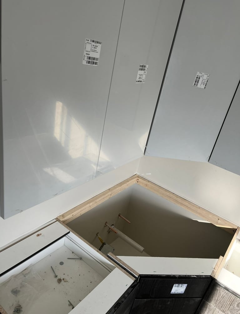 Open white cabinet with interior storage compartment showing bare wood frame and mounting brackets in corner