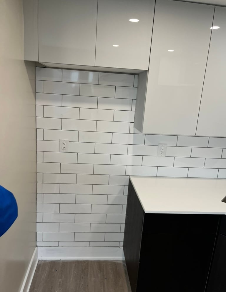Modern kitchen with white subway tile backsplash, white cabinetry, recessed lighting, and dark base cabinet