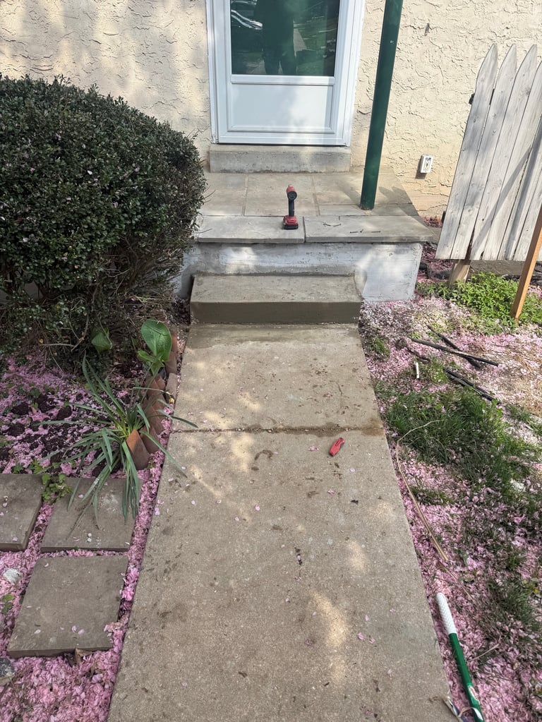 Pathway leading to a house entrance with pink mulch landscaping on both sides and green shrubs
