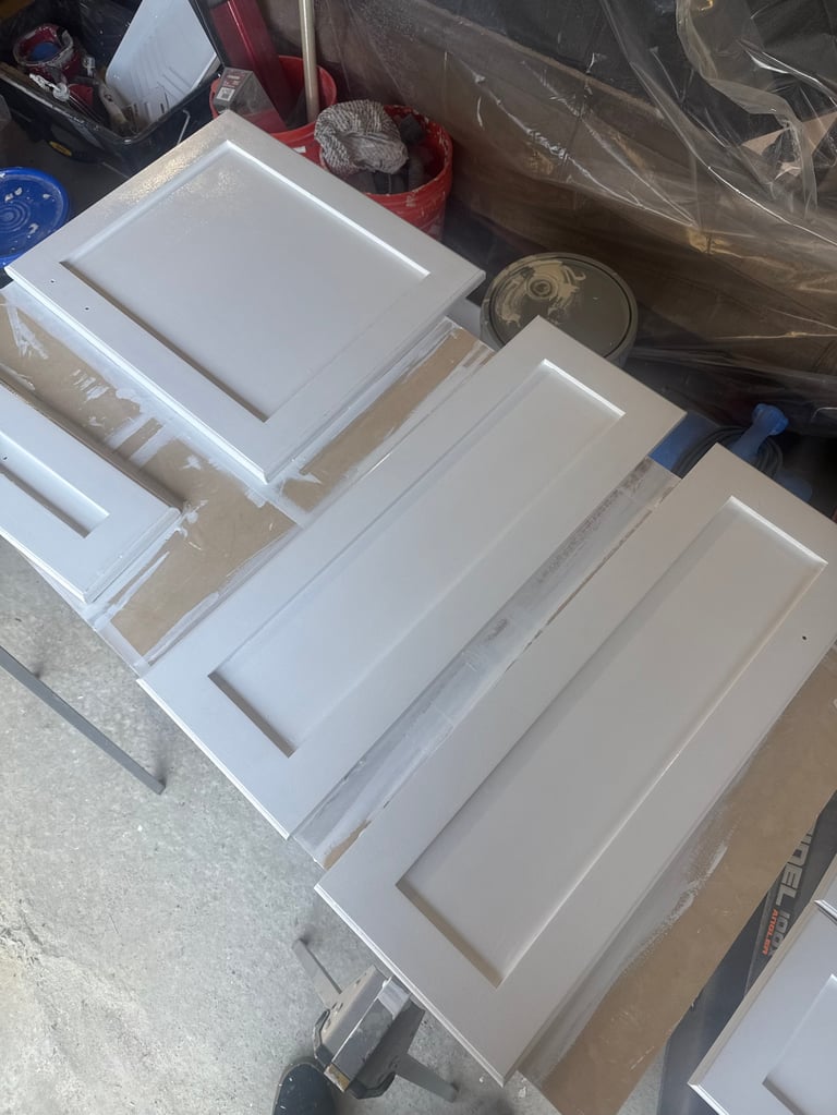 White cabinet doors and drawer fronts laid out in storage area
