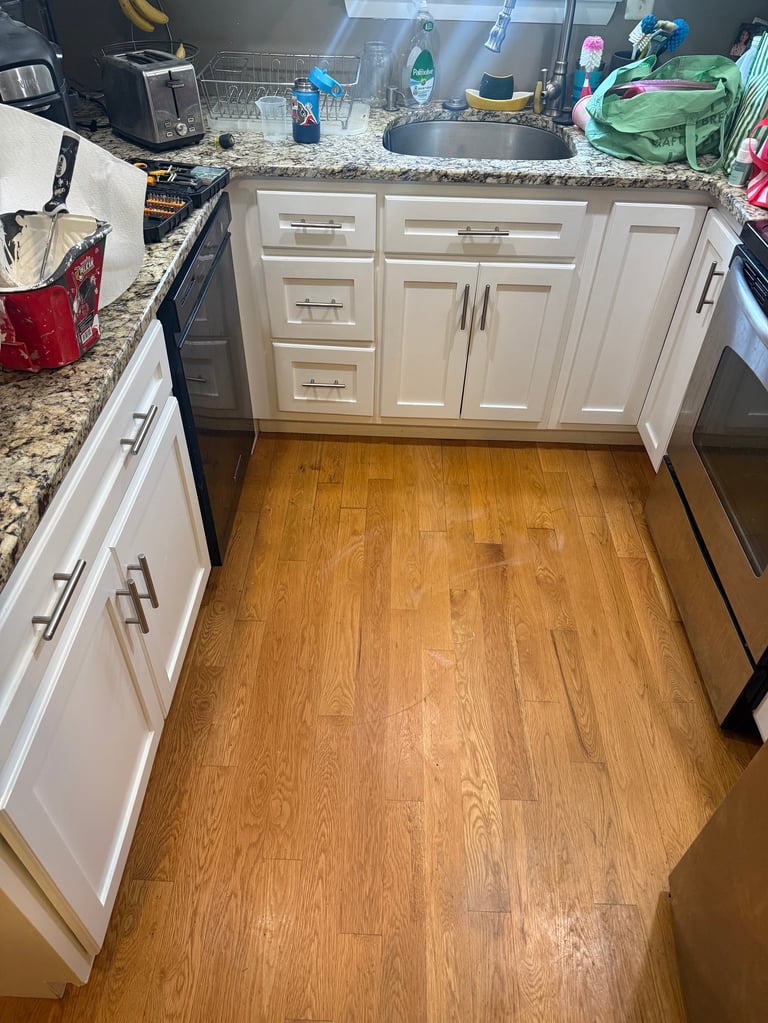 Kitchen with white cabinetry, granite countertops, stainless steel sink, and hardwood flooring, viewed from above