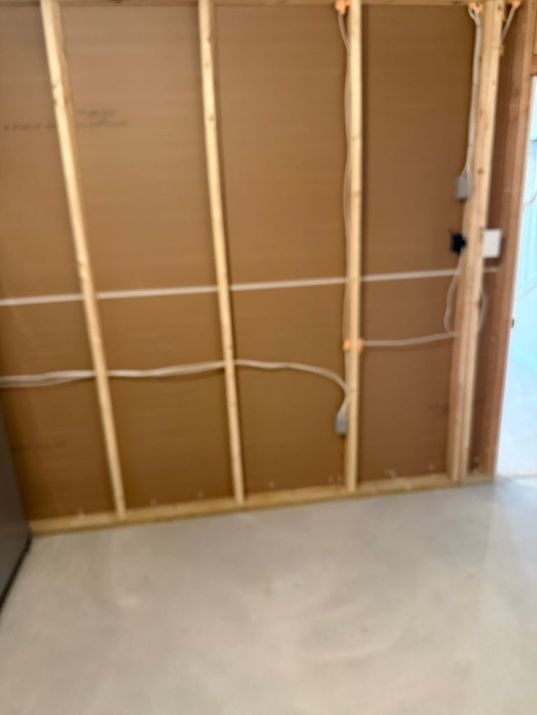 Wooden framed wall under construction with kraft paper panels and electrical wiring visible