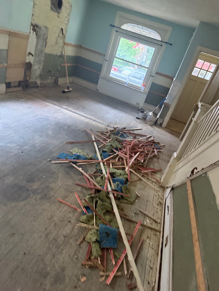 Empty room under renovation with scattered wood studs, wiring, and construction debris on the floor