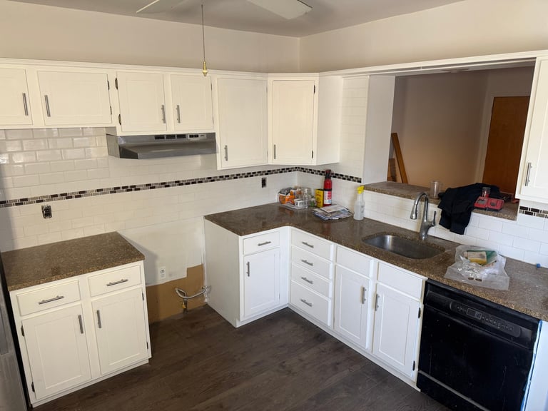 Modern kitchen with white cabinets, dark gray countertops, black appliances, and tiled backsplash
