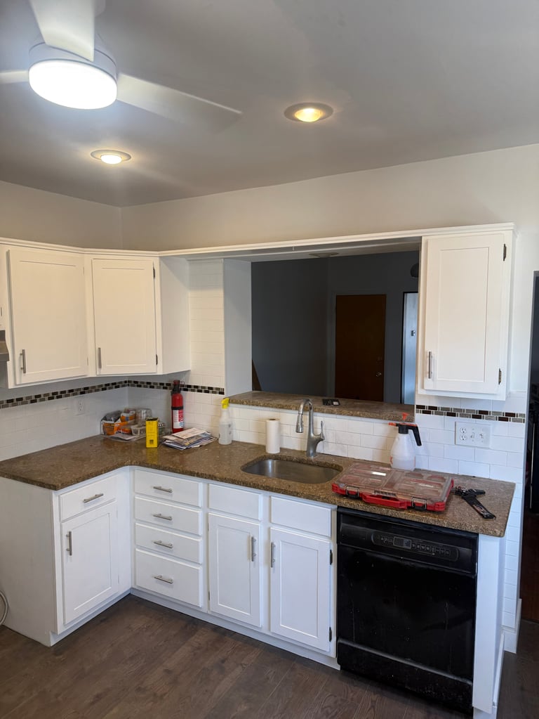 Modern kitchen with white cabinetry, granite countertops, black appliances, and recessed ceiling lights overlooking an open living area