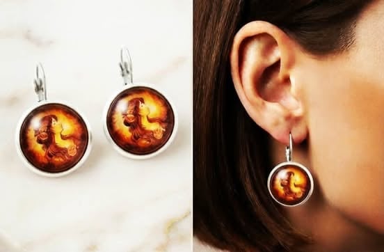 Pair of earrings featuring amber-colored resin domes with swirling designs, shown as a pair and worn on ear