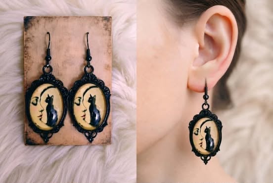 Pair of black silhouette cat and moon dangle earrings displayed on card and worn on persons ear