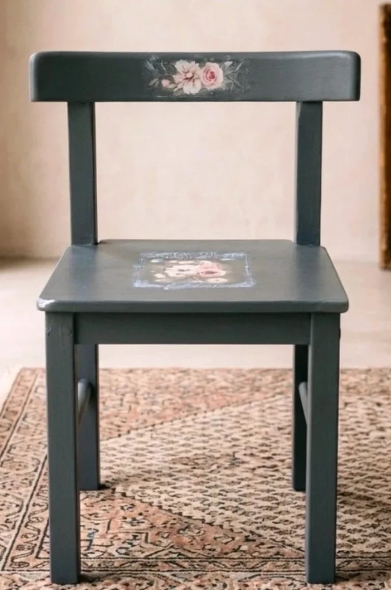 Dark green wooden chair with hand-painted rose design on backrest and seat, displayed on a patterned rug