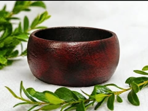 Two views of a polished dark red and brown wooden bracelet worn on a wrist