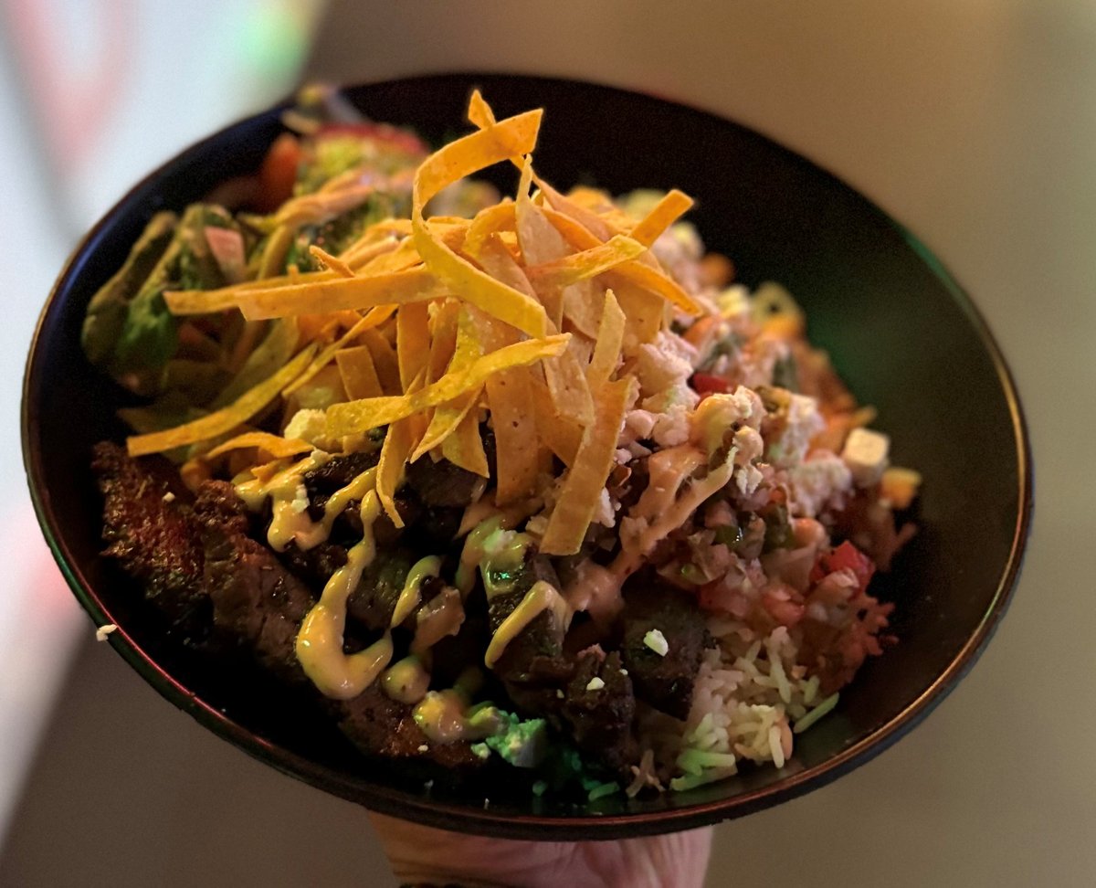 Steak Rice Bowl — grilled steak over rice with crispy tortilla strips, guacamole, and chipotle mayo