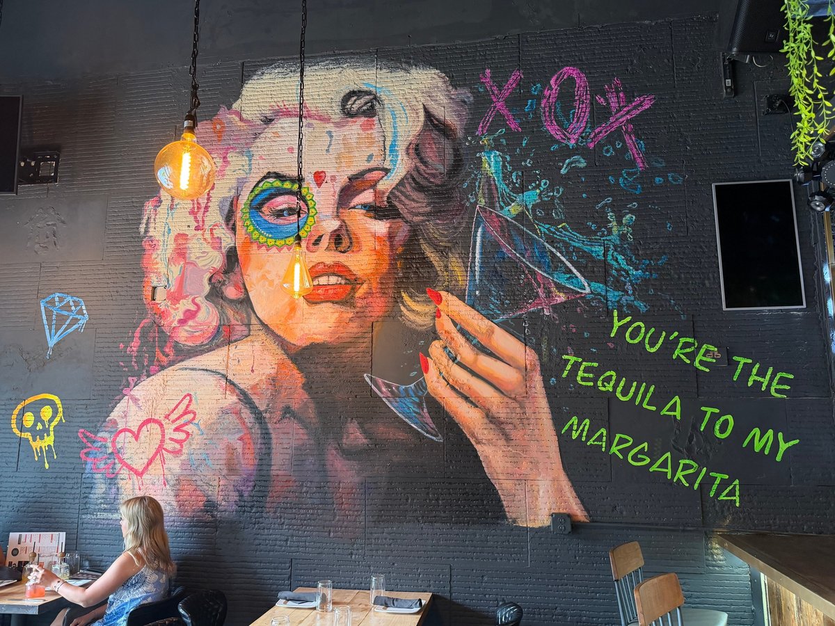 Colorful street art mural of a woman with makeup and glitter, with text reading You're the tequila to my margarita, inside Drunken Taco Bar