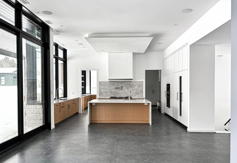 Modern minimalist kitchen with wooden island, white cabinetry, marble backsplash, concrete floors, and large black-framed windows