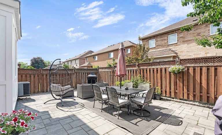 Backyard patio with dining table, chairs, and hanging egg chair overlooking fenced yard and residential homes