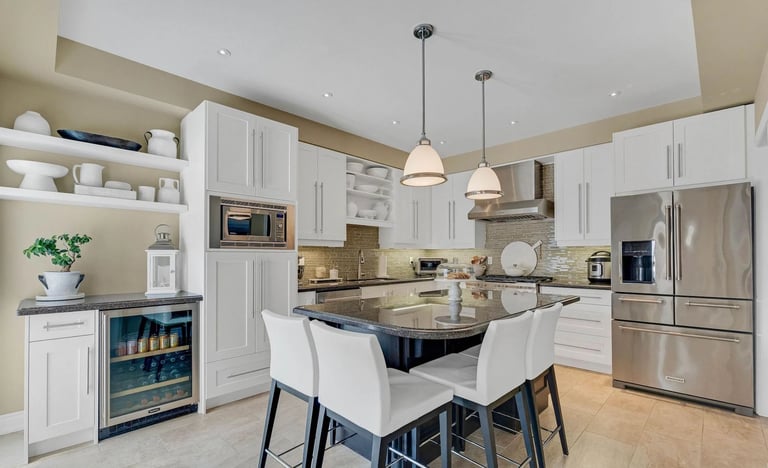 Modern kitchen with white cabinetry, stainless steel appliances, island with seating, and pendant lighting