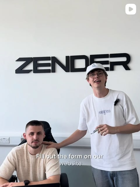 Two people in an office setting with ZENDER signage, standing and holding paperwork with text overlay reading Fill out the form on our website
