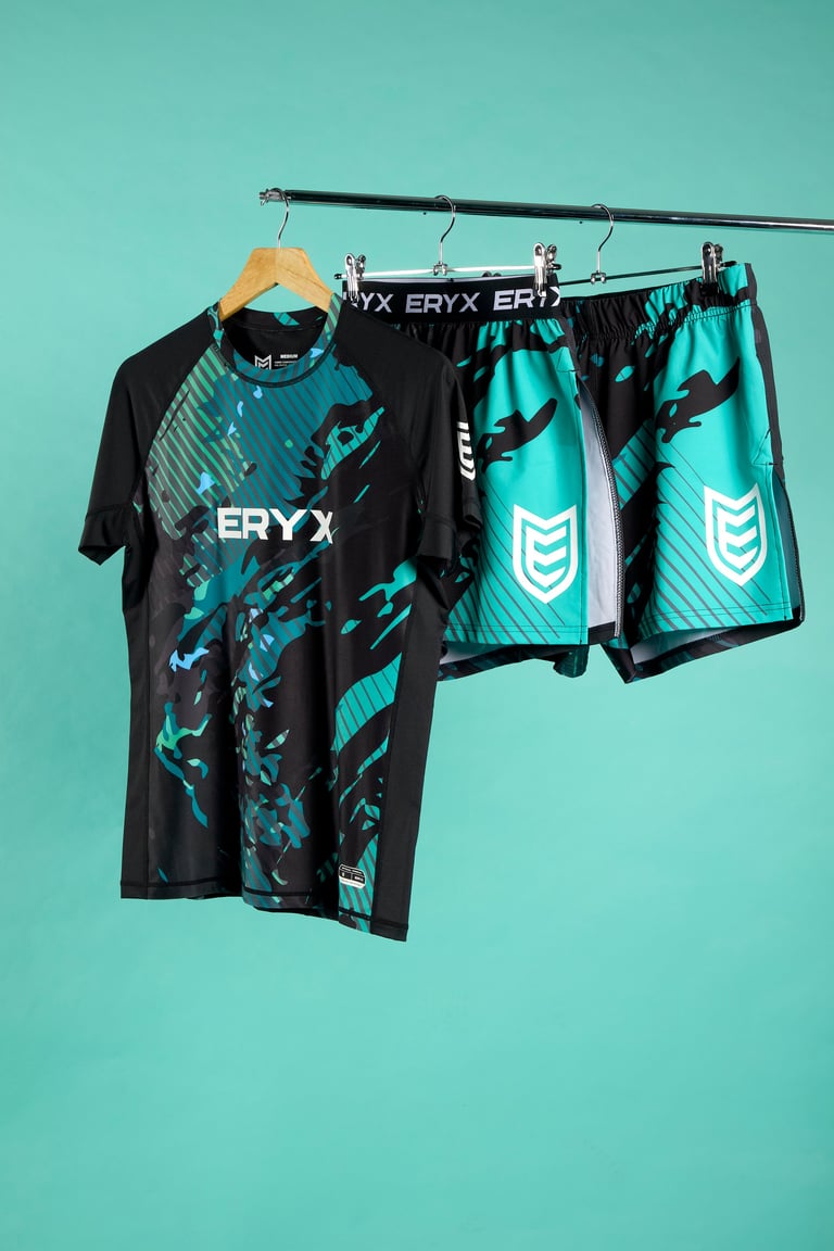 ERYX athletic clothing set hanging on a metal rod against a turquoise background, featuring a black and teal shirt and matching shorts