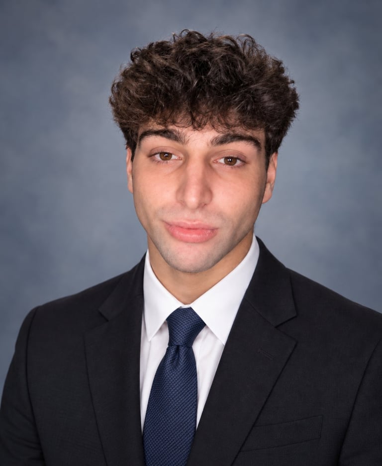 Professional headshot of Landon Newnam, founder of Cloudline AI, wearing a black blazer, white shirt, and navy tie against a blue-gray studio background