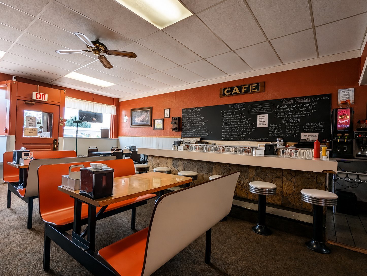 Bright orange cafe interior with booth seating, counter, menu board, and ceiling fan