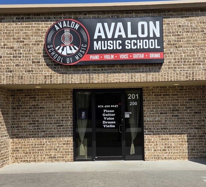 Avalon School of Music storefront with red and white sign on brick building, featuring piano, violin, voice, guitar, and drums instruction