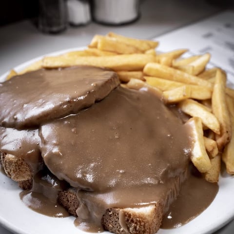 Chocolate-covered open-faced sandwich with golden fries on a white plate