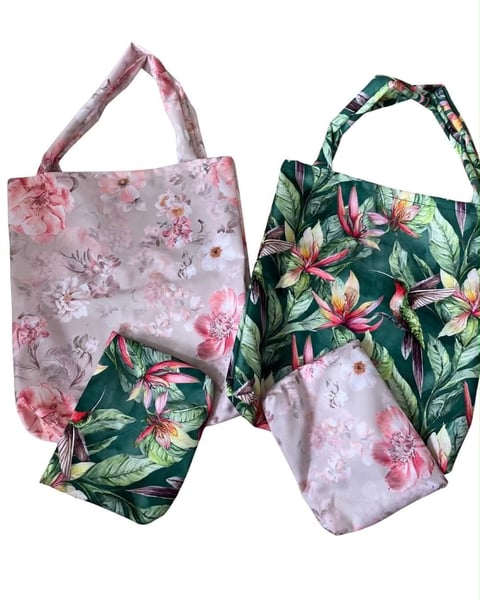 Two floral print fabric tote bags displayed with matching patterns of pink flowers and green foliage designs