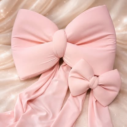 Two layered pink fabric bows on a soft beige textured background, with a larger bow and smaller accent bow