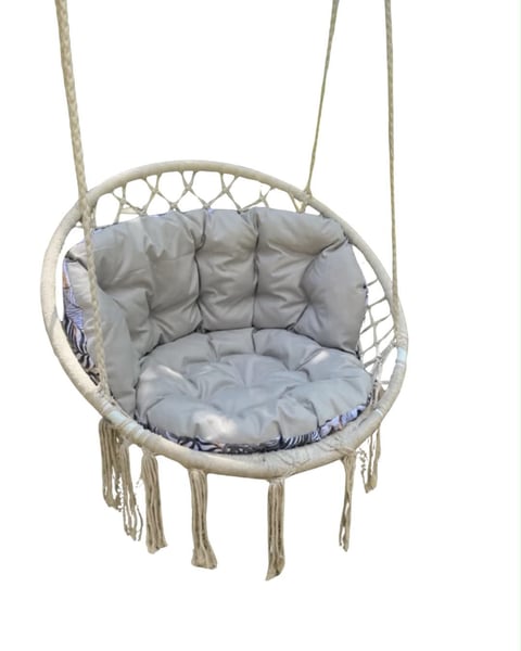 Hanging macrame swing chair with gray cushions and rope supports