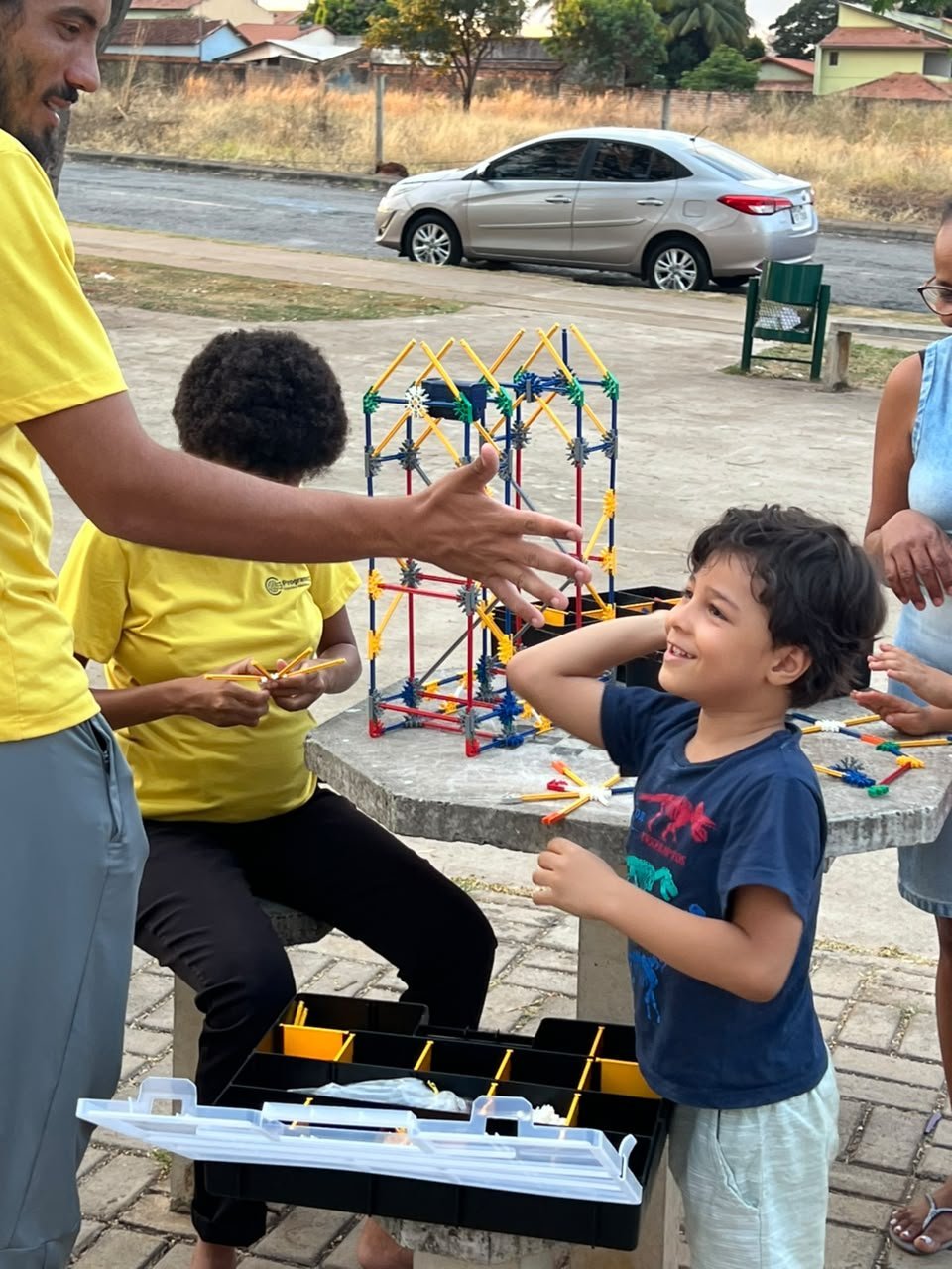 Adultos e crianças participam de atividade STEM com estruturas coloridas em evento comunitário