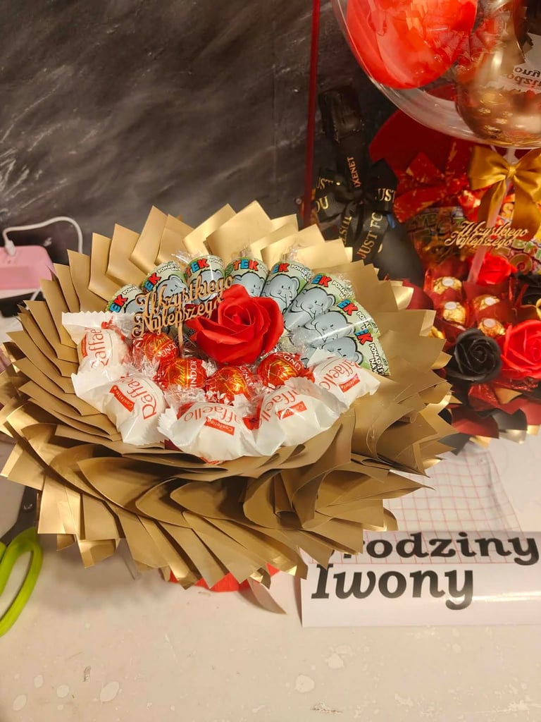 Wachlarzowy bukiet urodzinowy ze złotych papierowych płatków, czerwonej róży w środku, czekoladek Lindor, Raffaello i złotych słodywek, z drewnianym napisem Wszystkiego Najlepszego