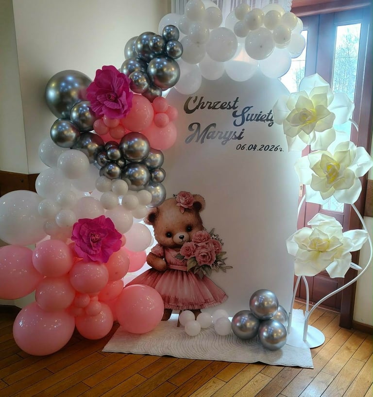 Decorative wedding backdrop with white banner, pink and silver balloons, floral arrangements, and a teddy bear decoration for a marriage celebration on 04.04.2026.
