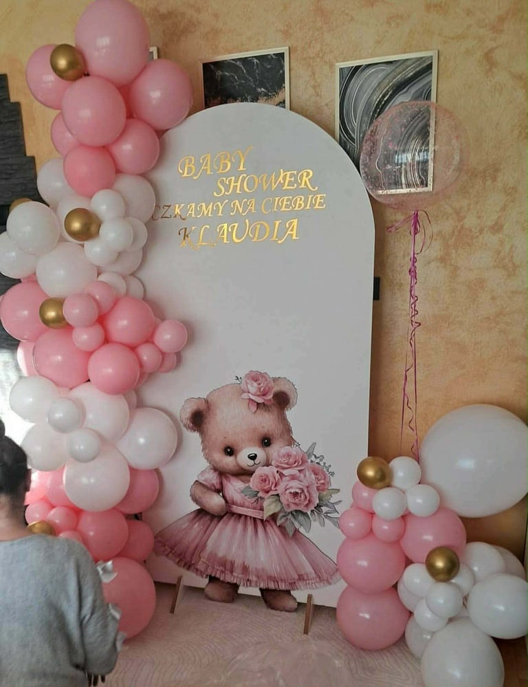 Tło baby shower z białym łukiem, różowymi i złotymi balonami oraz misiem z kwiatami