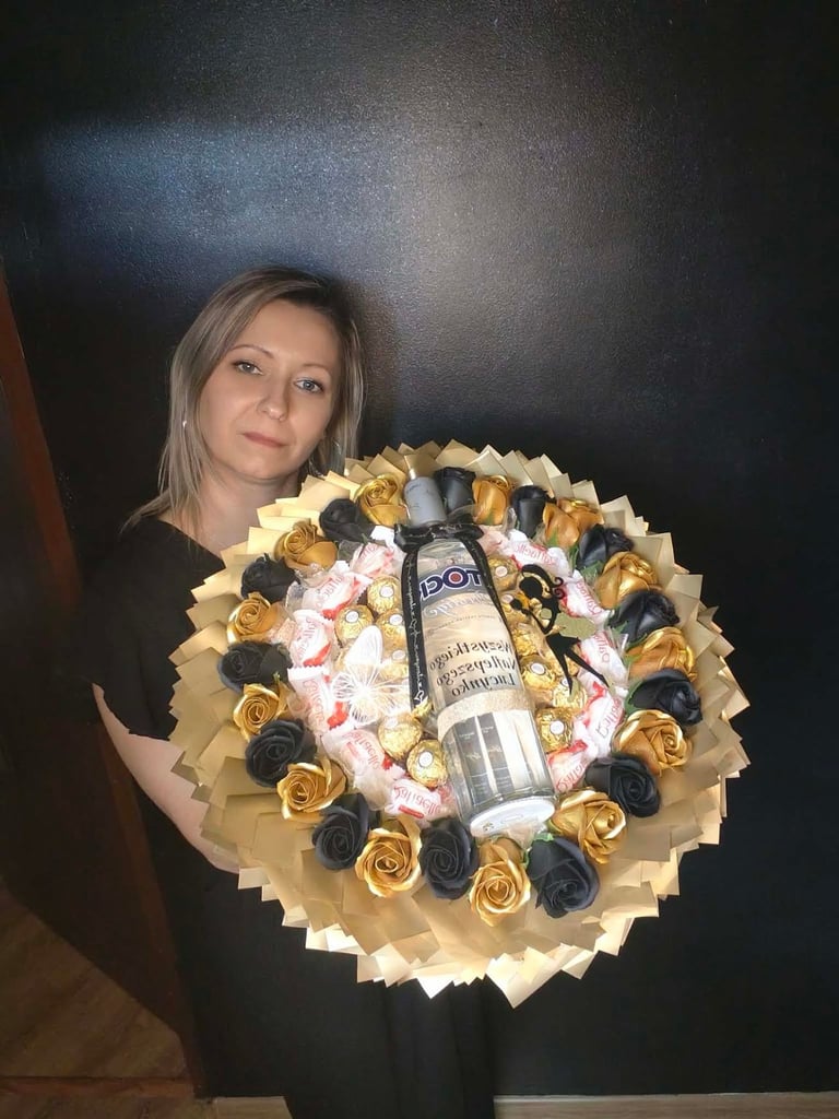 Kobieta trzymająca okazały bukiet złotych i czarnych mydlanych kwiatów z butelką Jack Daniel's pośrodku, w złotym papierze z różowymi dekoracjami