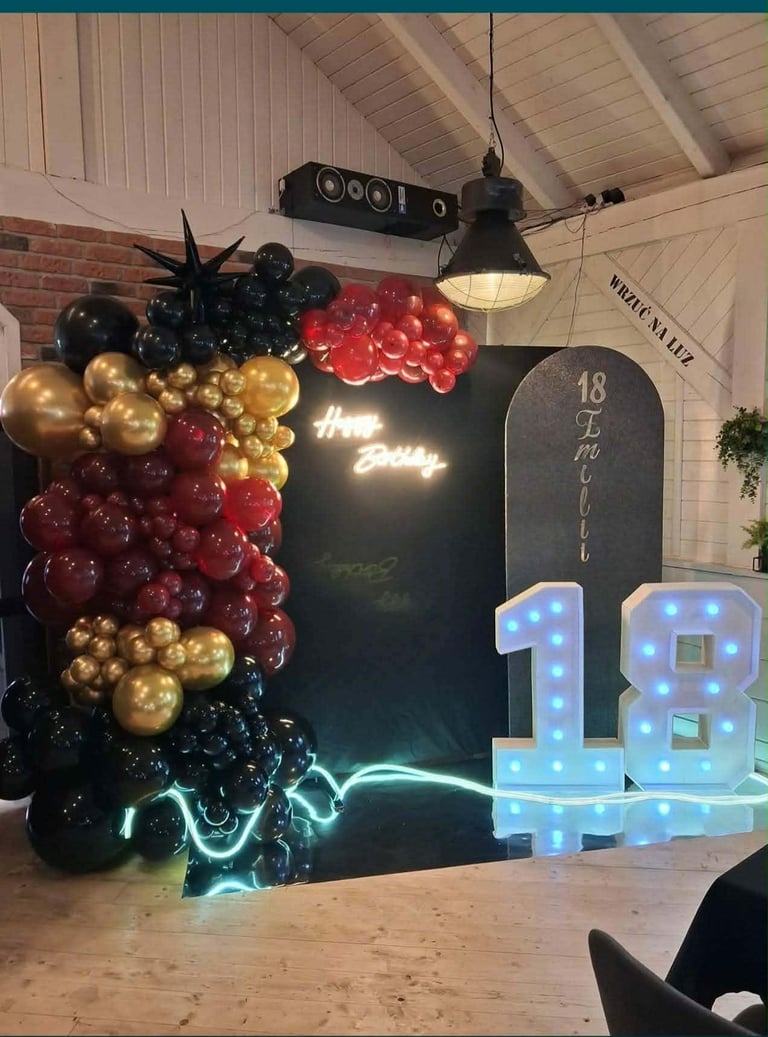 Ścianka 18-stka Emilii z czarno-złoto-czerwonym łukiem, neonem Happy Birthday, tablicą i podświetlaną cyfrą 18 w industrialnej sali
