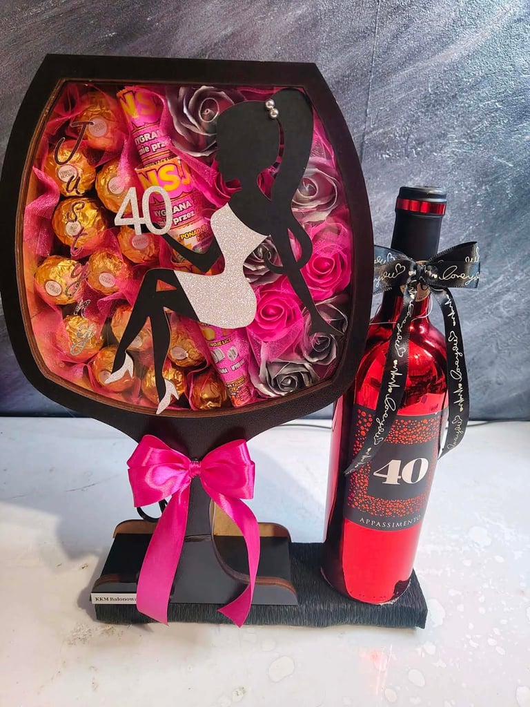 Ozdobny flowerbox w kształcie kieliszka ze złotą sylwetką siedzącej kobiety, wypełniony złotymi Ferrero Rocher, złotymi różami, loteriami i rachunkami Super Szans, z czerwoną wstążką Just For You