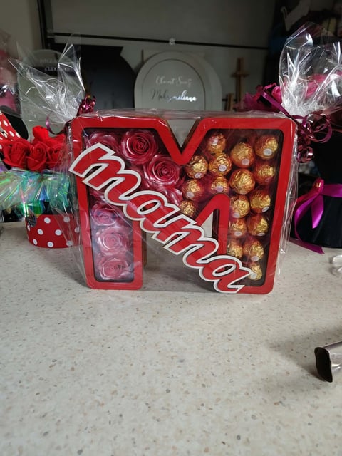 Red heart-shaped Amor box filled with chocolate truffles on a counter, surrounded by wrapped gift boxes