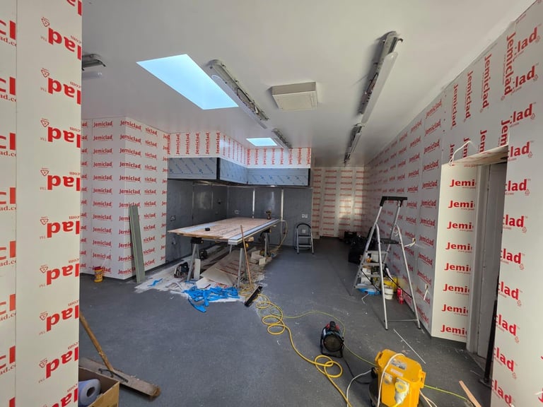 Construction site interior with work table, tools, yellow extension cords, and red branded wall insulation panels