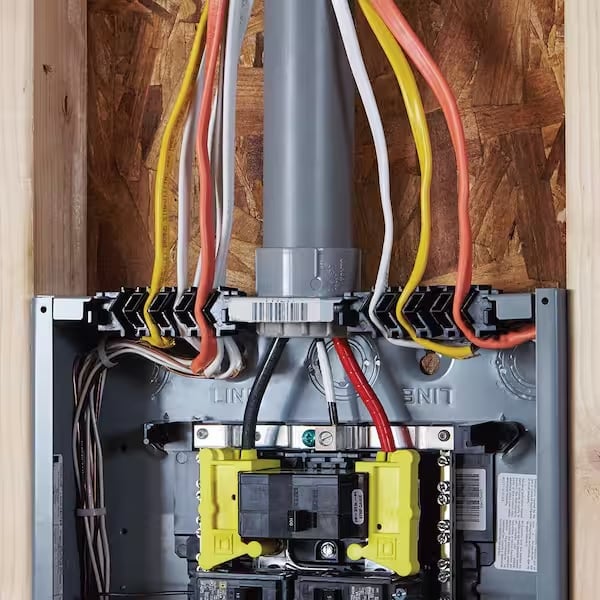 Electrical panel with colored wires connected to a yellow breaker switch and terminal blocks mounted on wooden backing