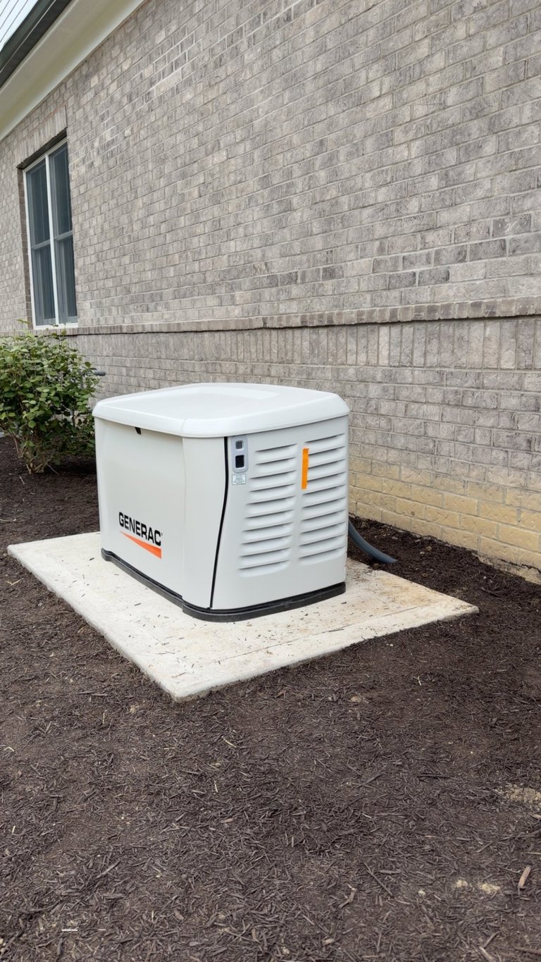 White Generac standby generator professionally installed on concrete pad against brick house exterior — Dylco Electric installation in Westfield, IN