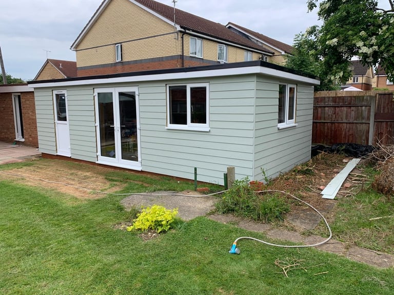 Light blue garden room with white trim and dark windows in residential backyard