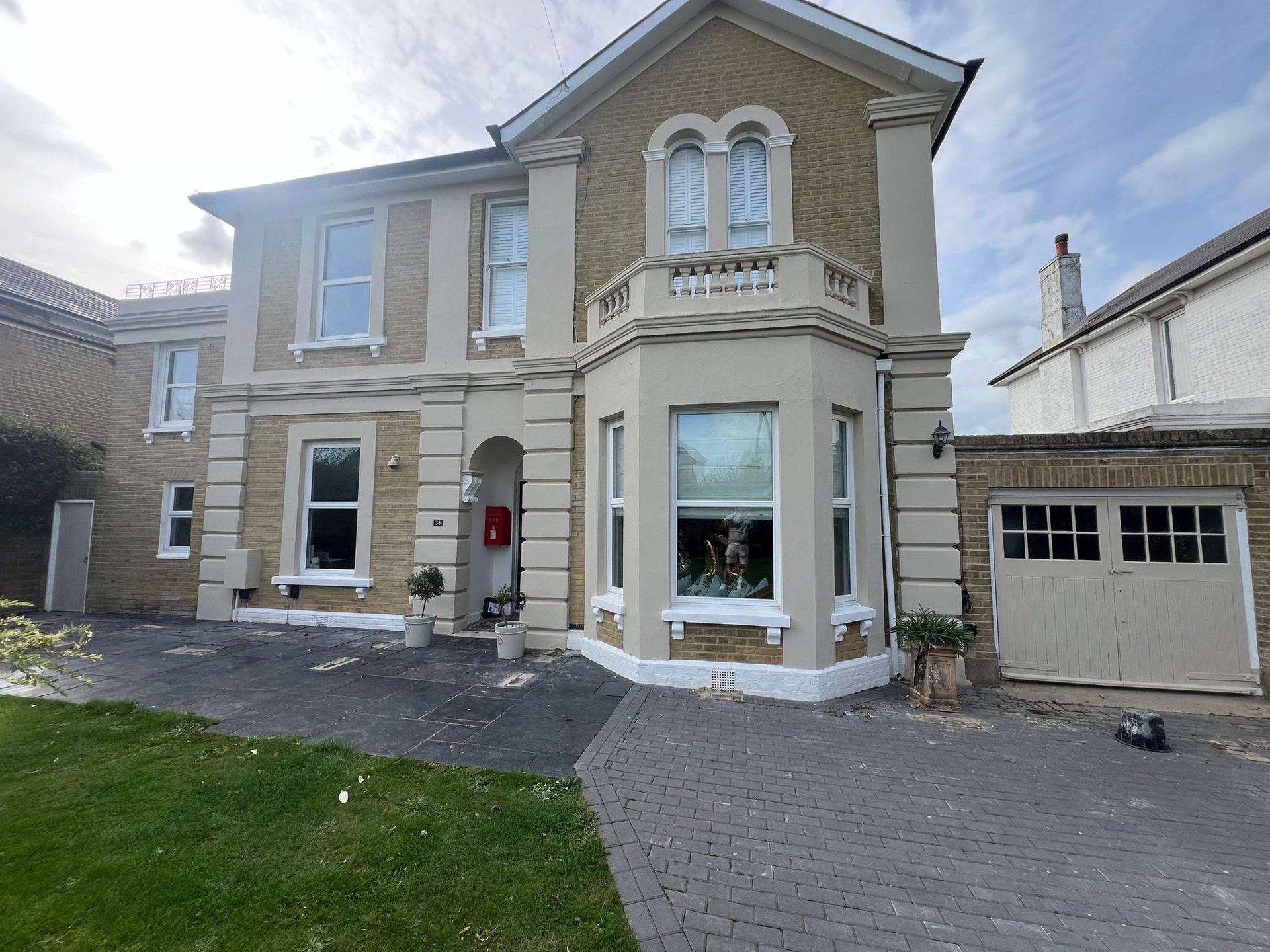 Two-story stone townhouse with attached garage, manicured lawn, and paved driveway on a sunny day.