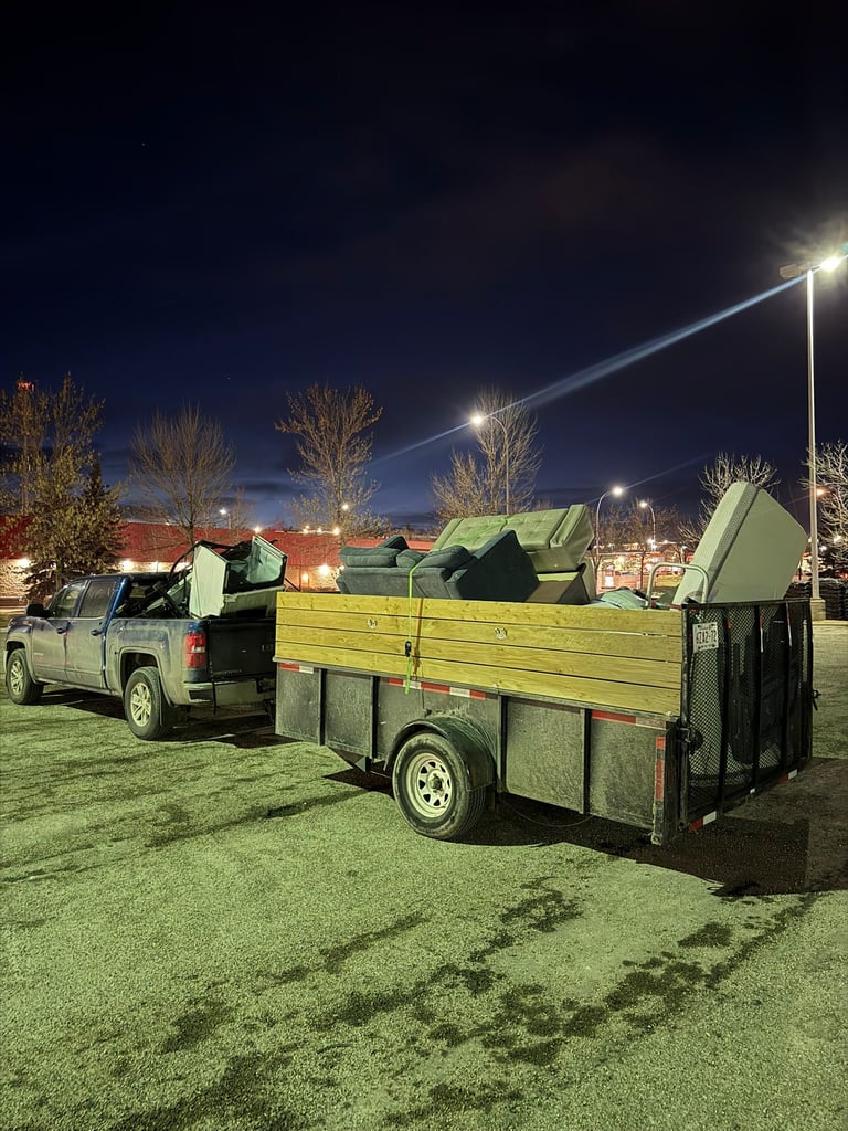 Pickup truck loaded with hay bales attached to a trailer parked in a lit field at night