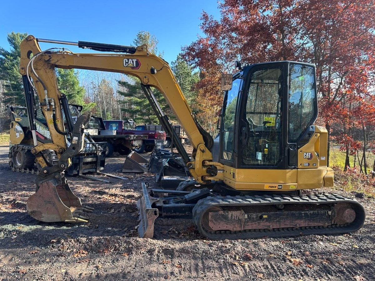 Holsclaw Building's CAT 305 mini excavator parked at the equipment yard with autumn trees in the background