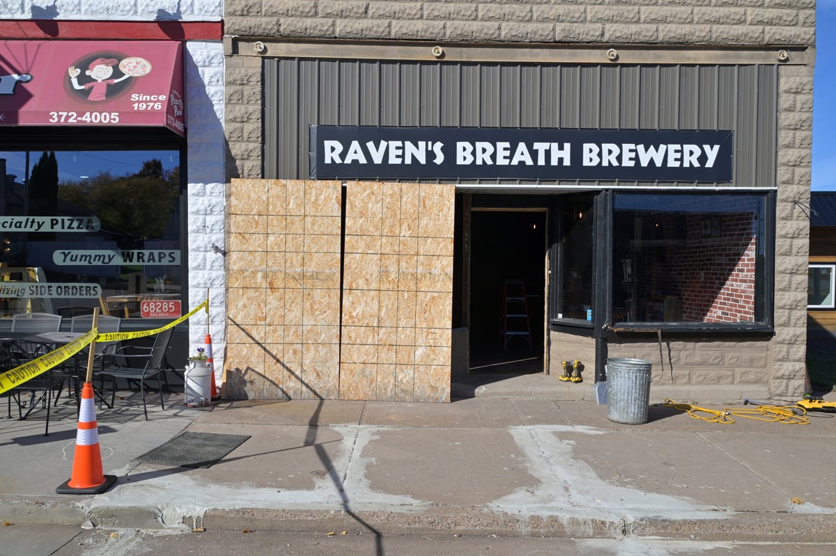 Storefront of Raven's Breath Brewery with gray stone facade and damaged front entrance after a vehicle collision