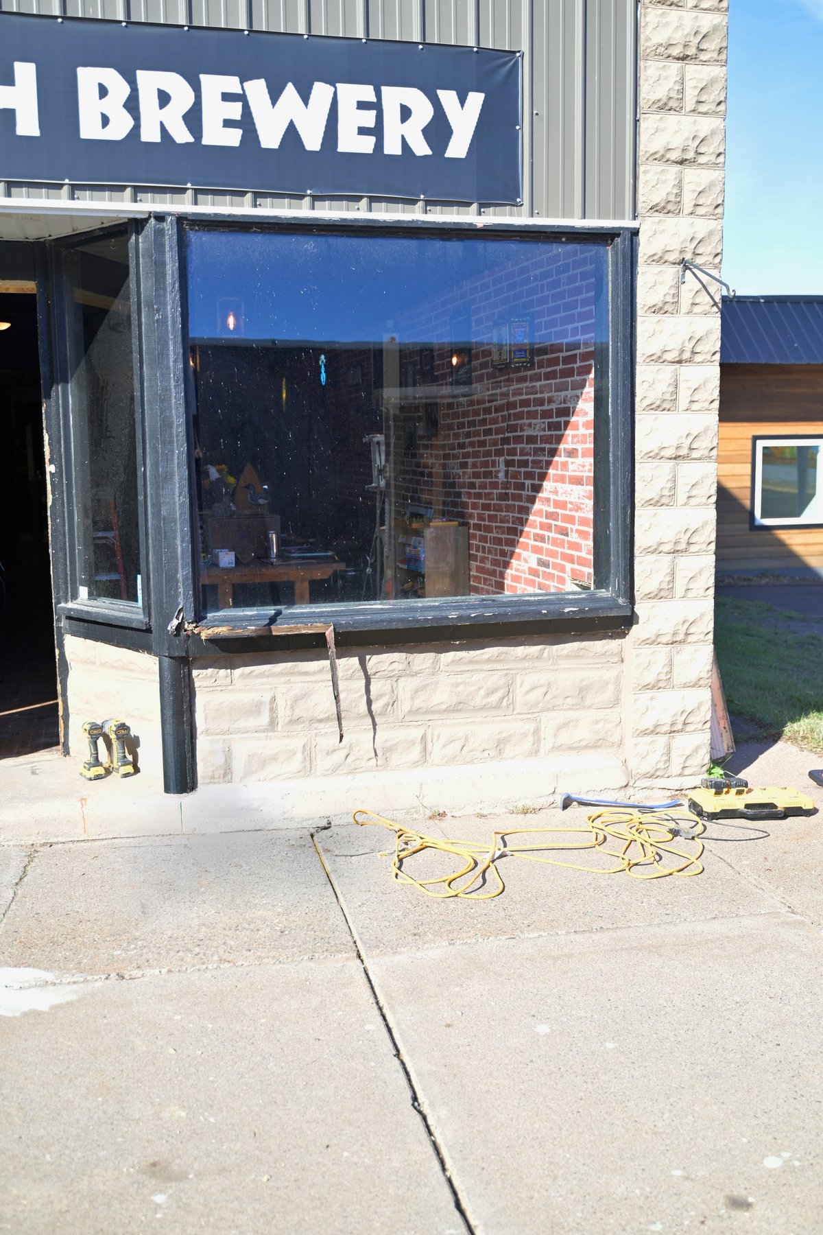 Brewery storefront with blue Raven's Breath Brewery signage and the bay window under repair after the collision