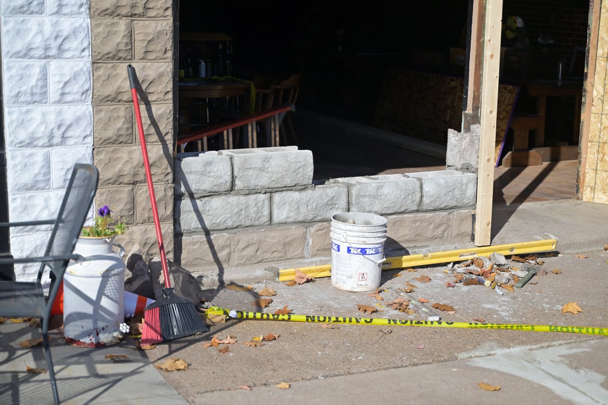 Brewery construction site entrance with yellow caution tape, broom, concrete blocks, and white bucket during emergency repairs